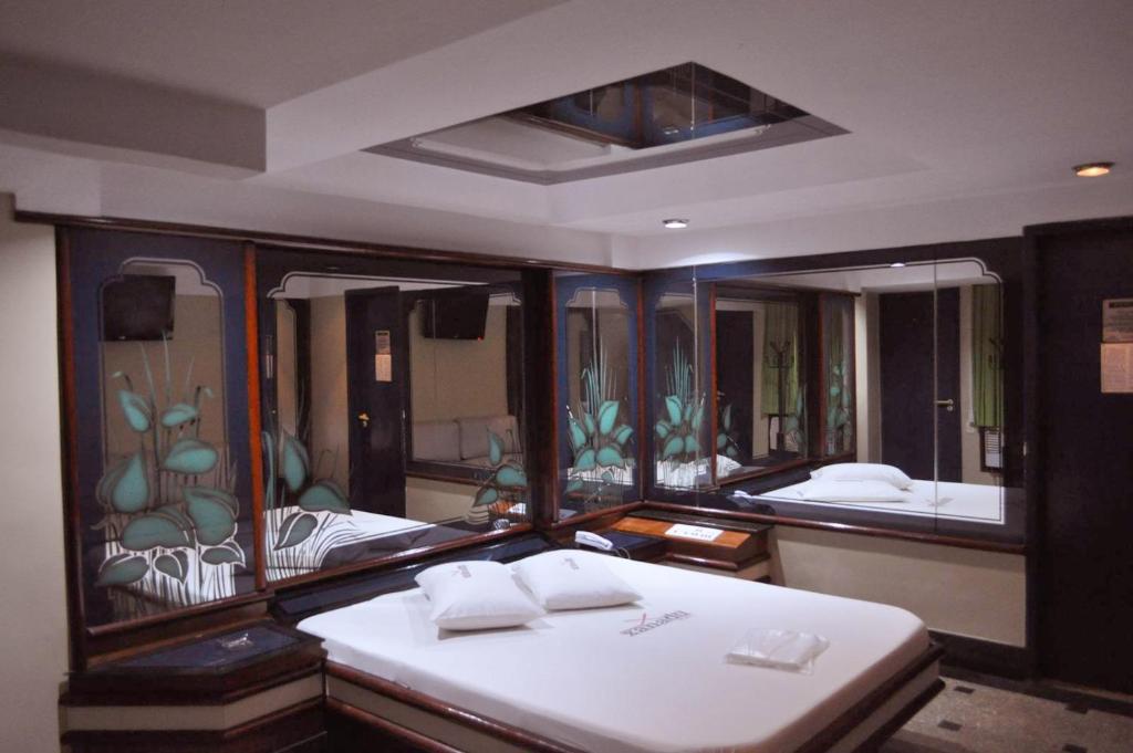 Hotel Xanadu - Adults Only في ريو دي جانيرو: غرفة بسريرين ومرآة كبيرة