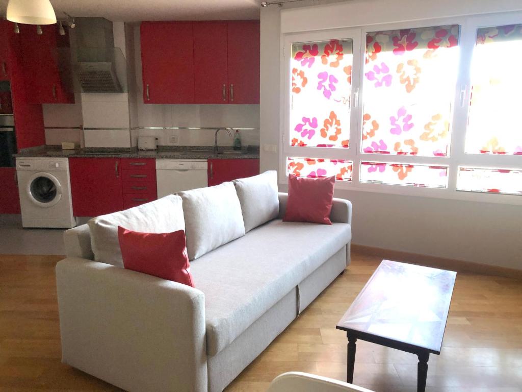 sala de estar con sofá blanco y almohadas rojas en Apartamentos Noluna, en Segovia