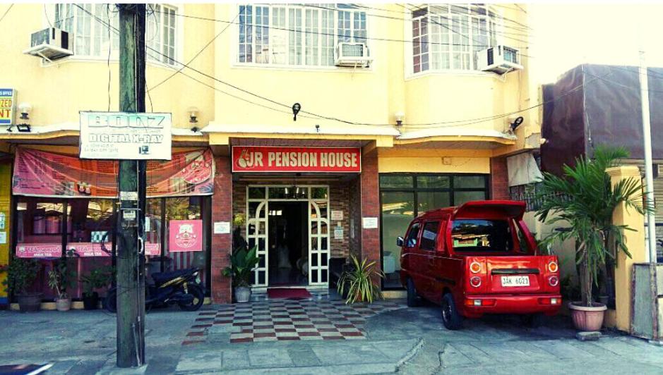 une camionnette rouge garée devant un bâtiment dans l'établissement JR Pension House, à Baybay