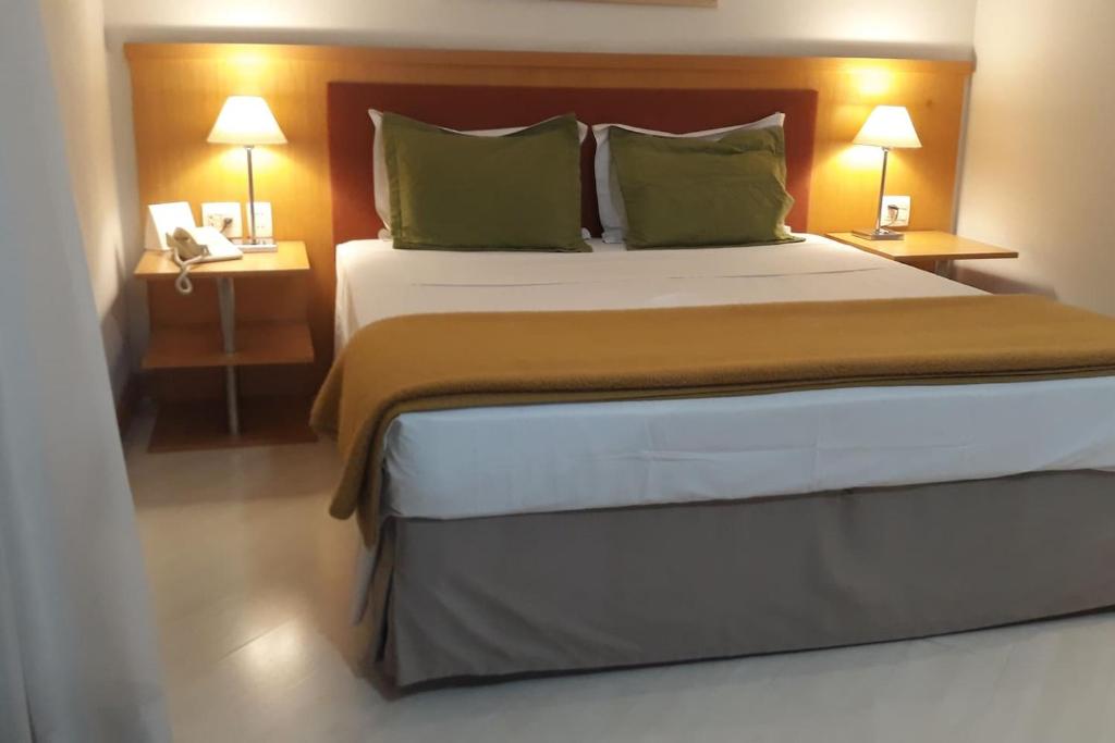 a large bed in a hotel room with two lamps at Flat com Sacada - Região Ibirapuera próximo vários Hospitais e UNIFESP in Sao Paulo