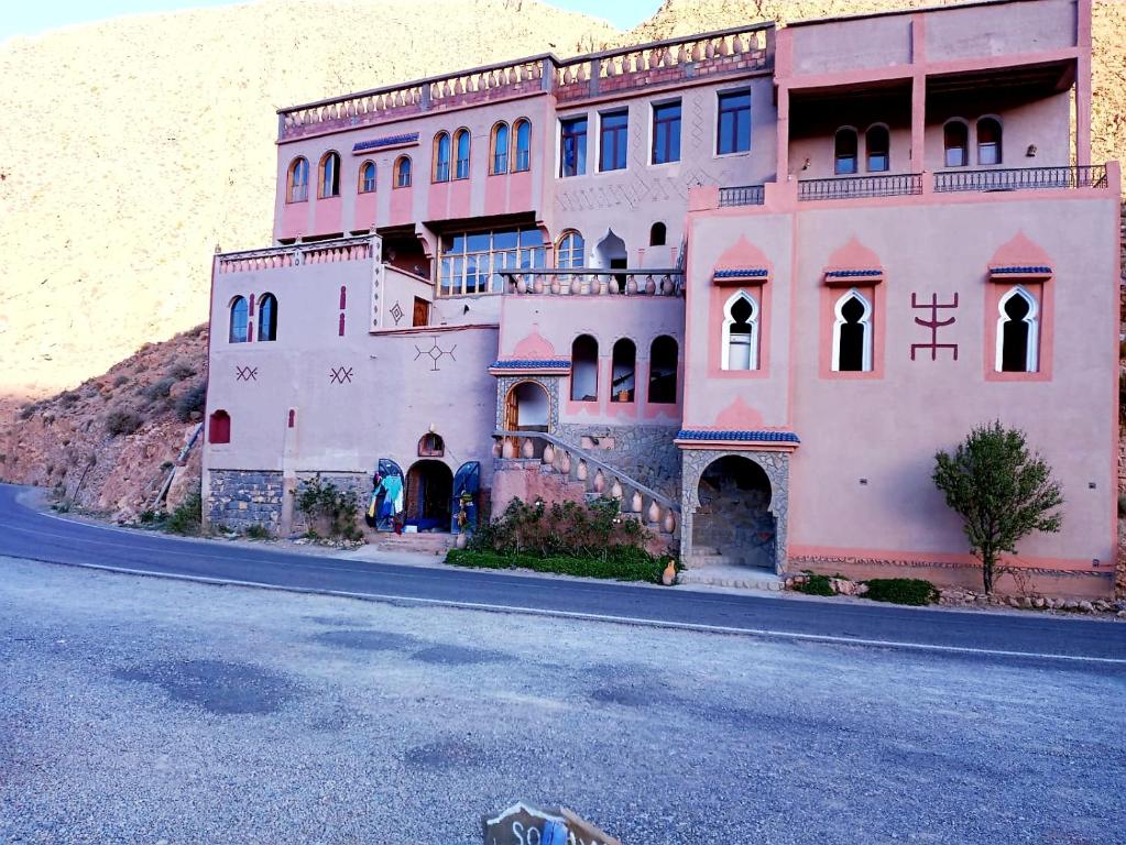 um grande edifício cor-de-rosa ao lado de uma estrada em Riad Bleu Afriqua em Boumalne Dadès