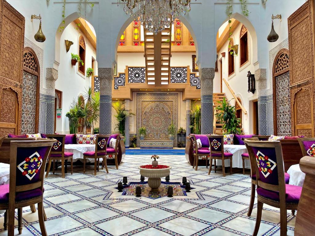 een restaurant met tafels en stoelen en een kroonluchter bij Riad Marjana suites & Spa in Fès