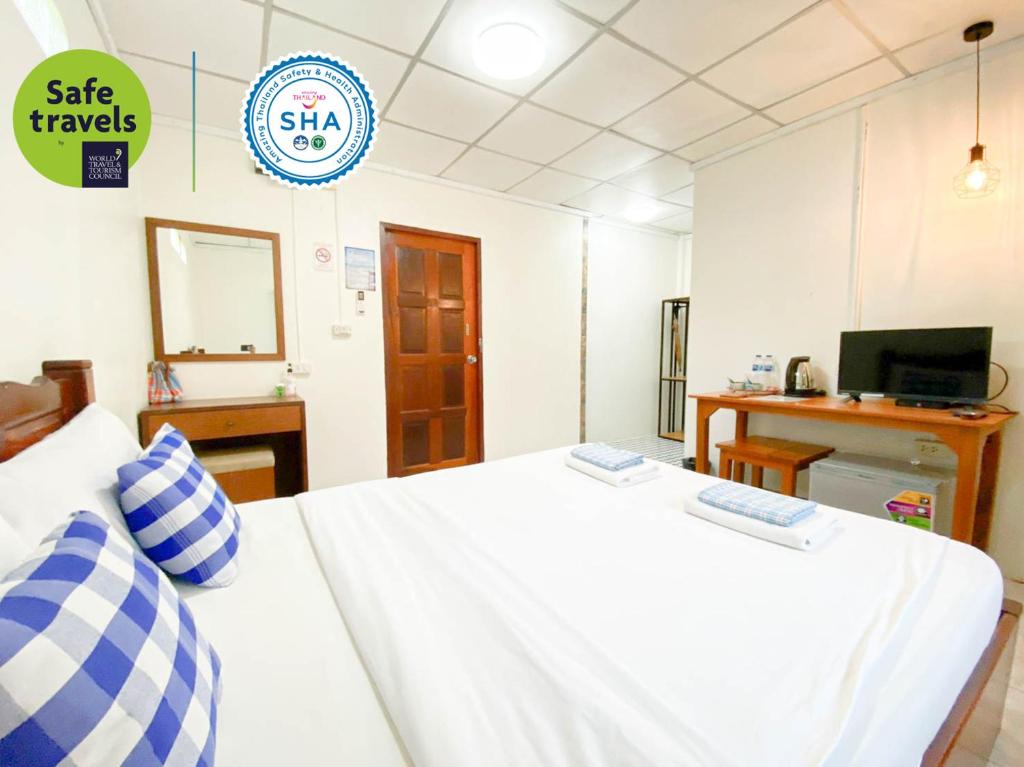 um quarto com uma cama branca, uma secretária e uma televisão em Bell House Resort em Ko Samet