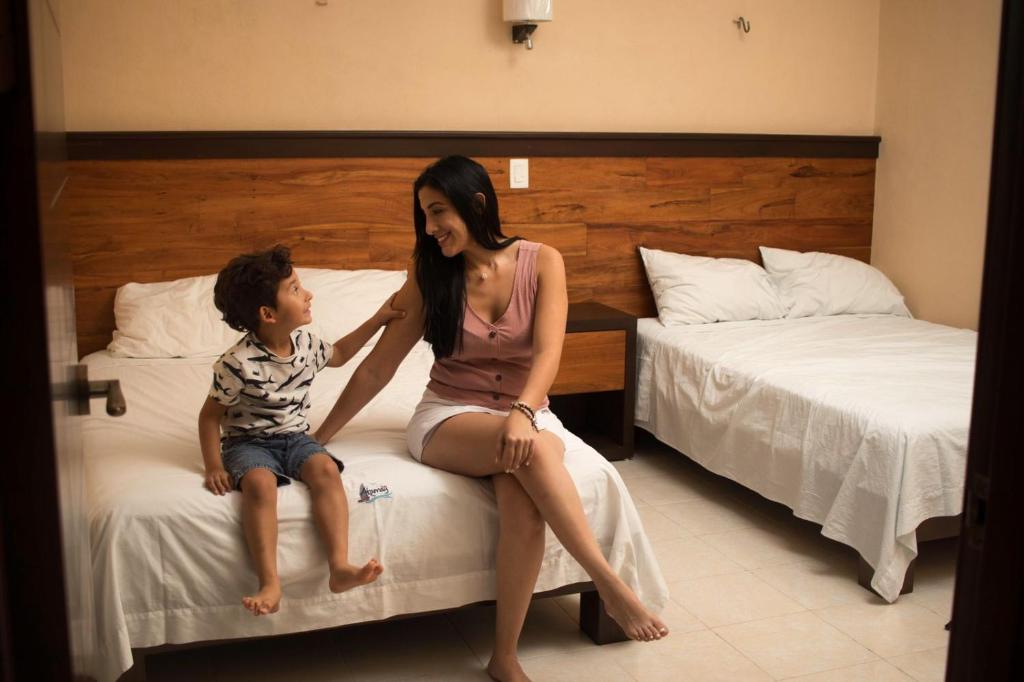 a woman and a child sitting on a bed at Apartamento Akamay 2 in El Cuyo