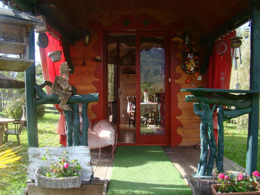 una cabaña de madera con una puerta roja y algunas plantas en Les Patins à Roulottes en Yenne