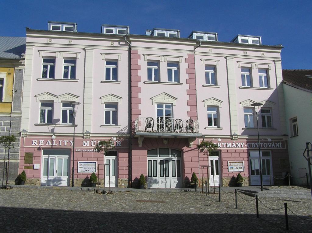 un gran edificio rosa y blanco en una calle en Apartmány na Šumavě en Kašperské Hory