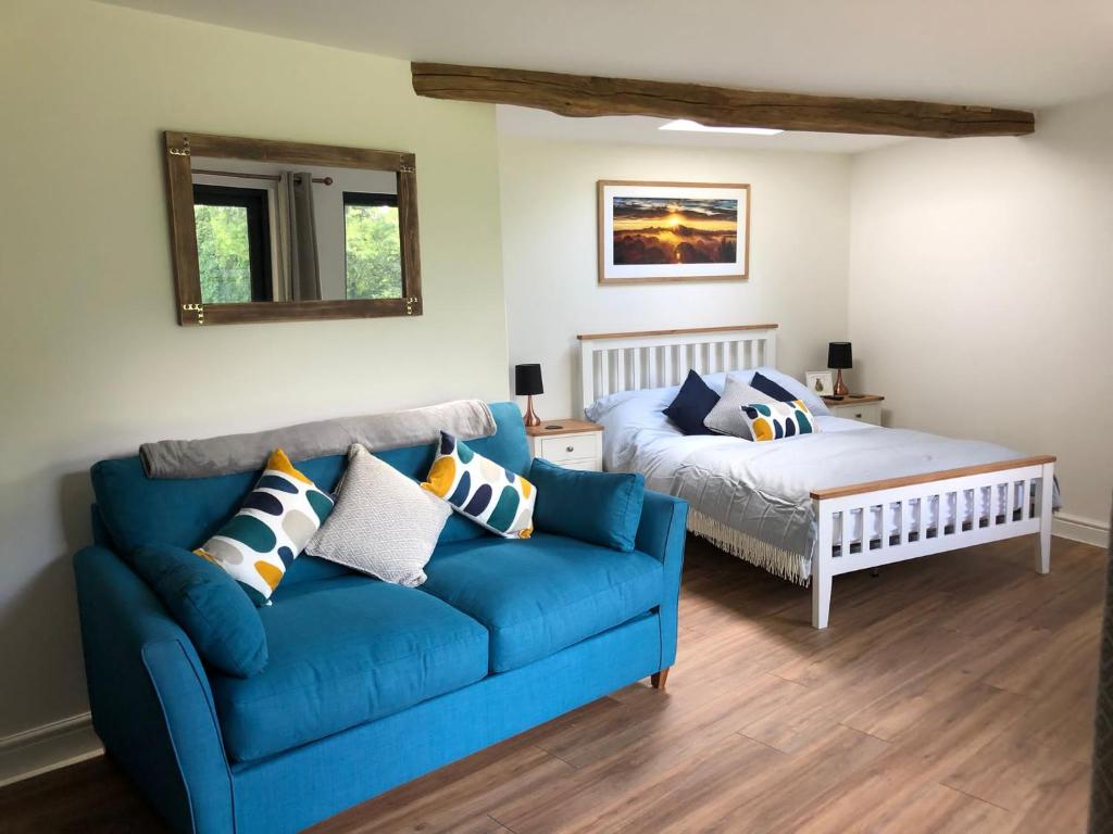 uma sala de estar com um sofá azul e uma cama em Conkers - a new bespoke rural escape near Glastonbury em Glastonbury