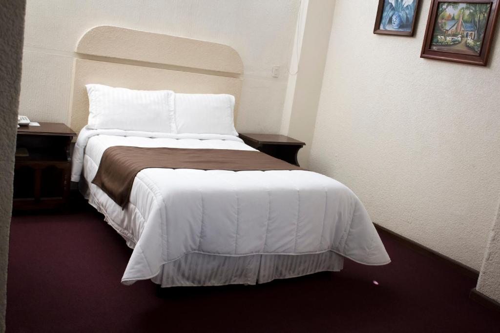 Habitación de hotel con cama con sábanas blancas en HOTEL ROMO, en Ciudad Hidalgo