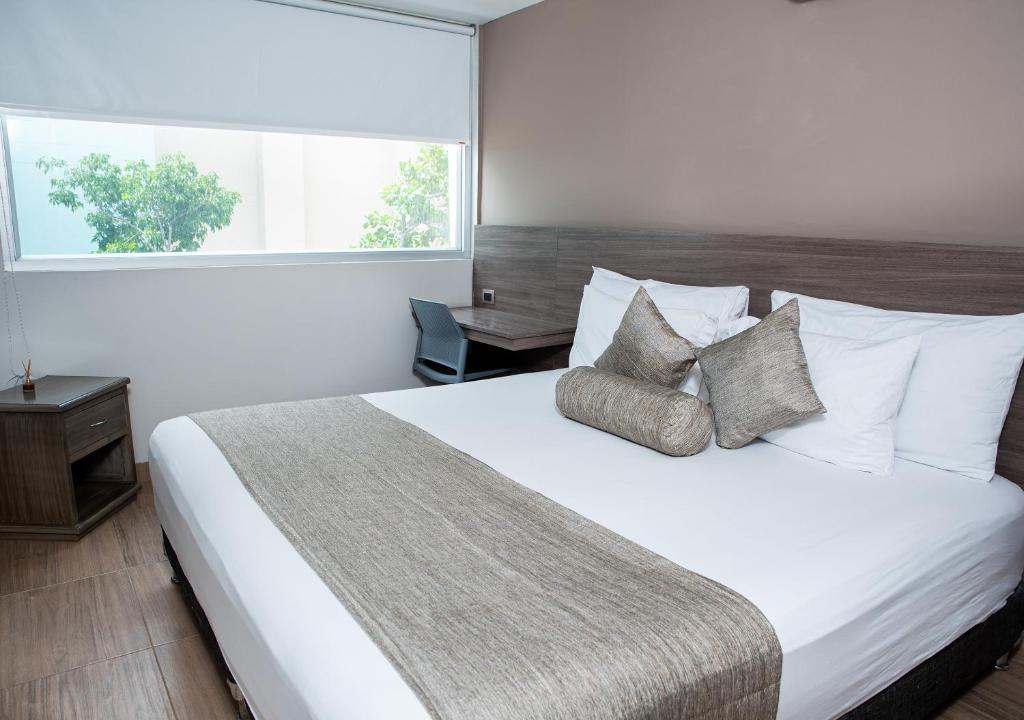 Un dormitorio con una cama blanca con almohadas y una ventana. en Hotel Betania, en Santa Marta