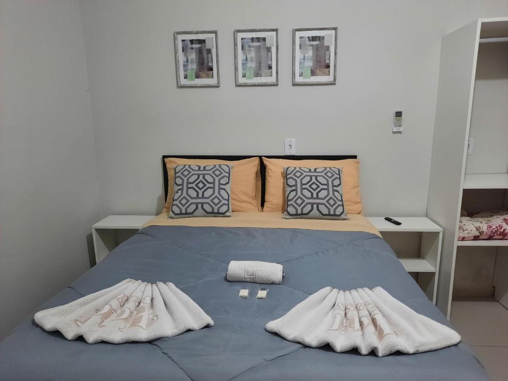 a bedroom with a blue bed with two pillows at Hotel Três Passos - Prox ao Aeroporto e Rodoviária in Porto Alegre