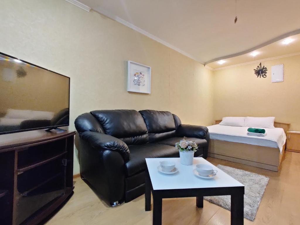 a living room with a leather couch and a bed at Apartament on Gorkogo 26 in Bobruisk