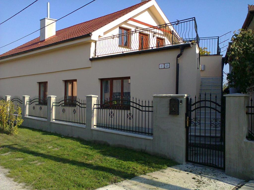 a white house with a fence and a yard at Apartman Vilo in Veľký Meder