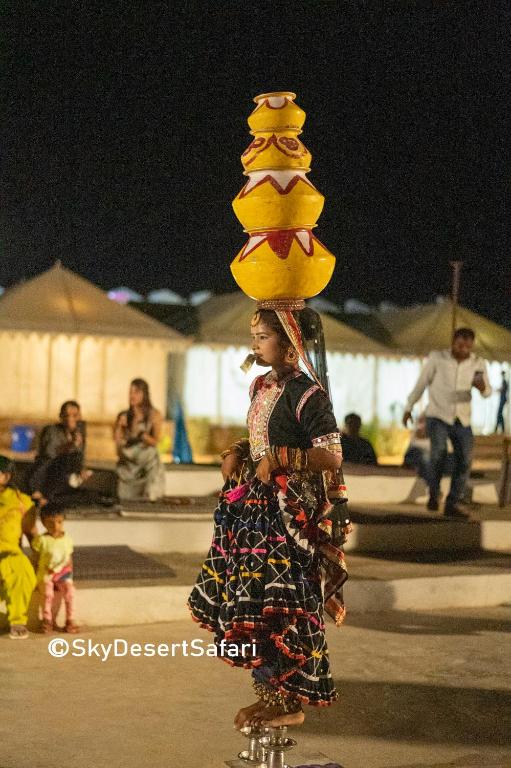 a woman riding a skateboard with a stack of hats on her head at Sky Desert Safari in Sām