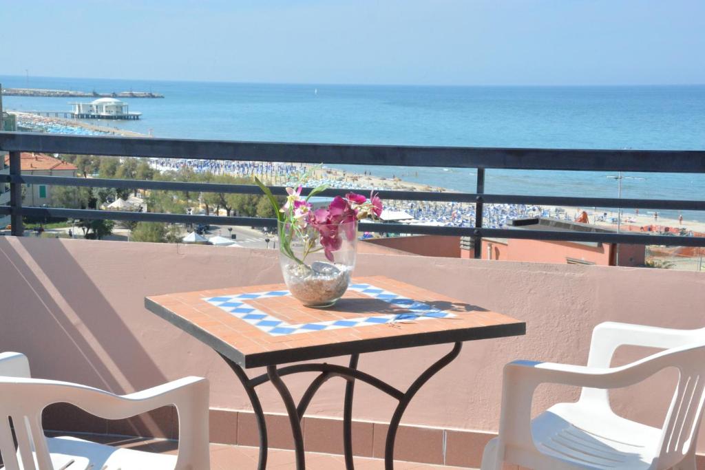 a table with a vase of flowers on a balcony with the beach at Hotel Cristina in Senigallia