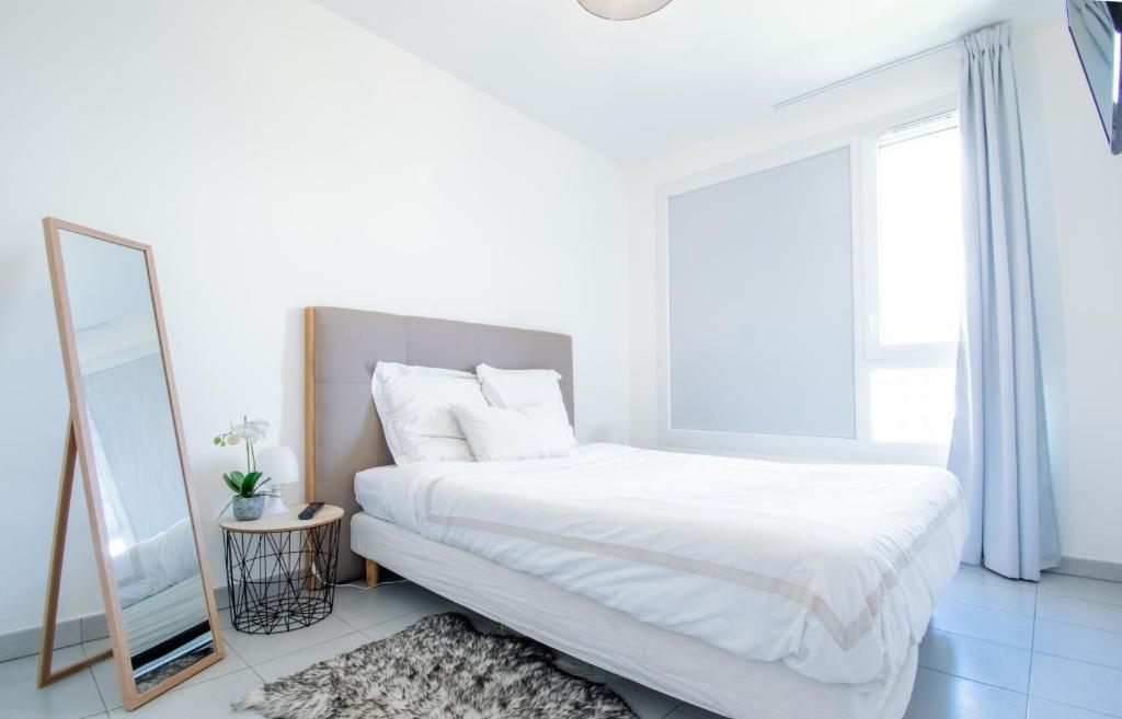 a white bedroom with a bed and a mirror at °Le métropole° Check in H24/wifi in Lyon