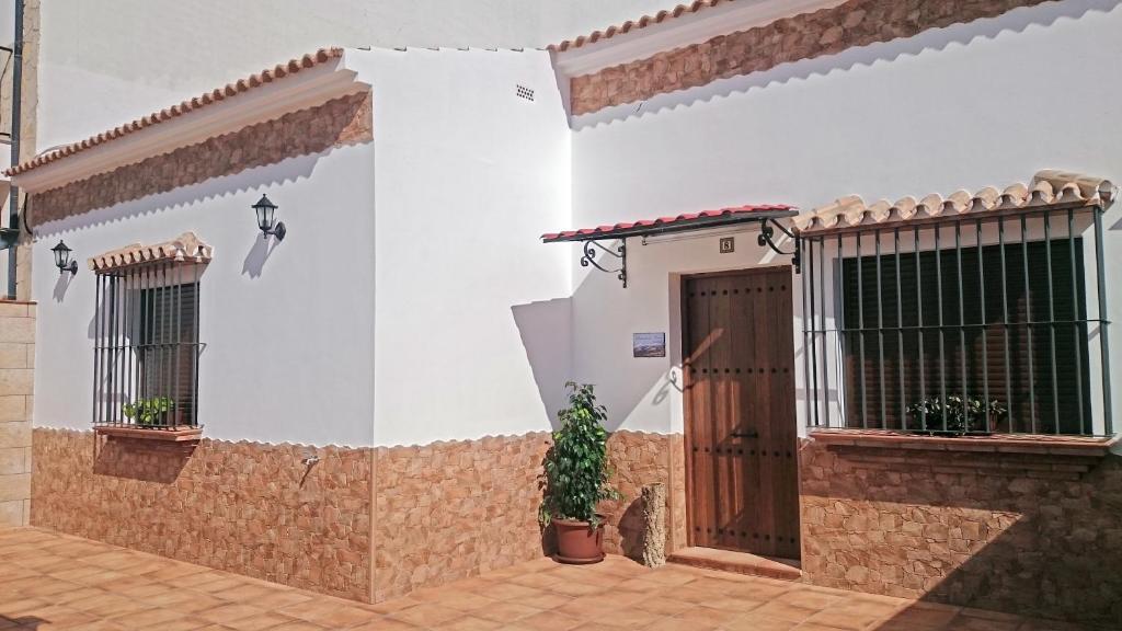 Casa Rural Sierra de las Nieves في Yunquera: بيت ابيض فيه باب وزرع الفخار