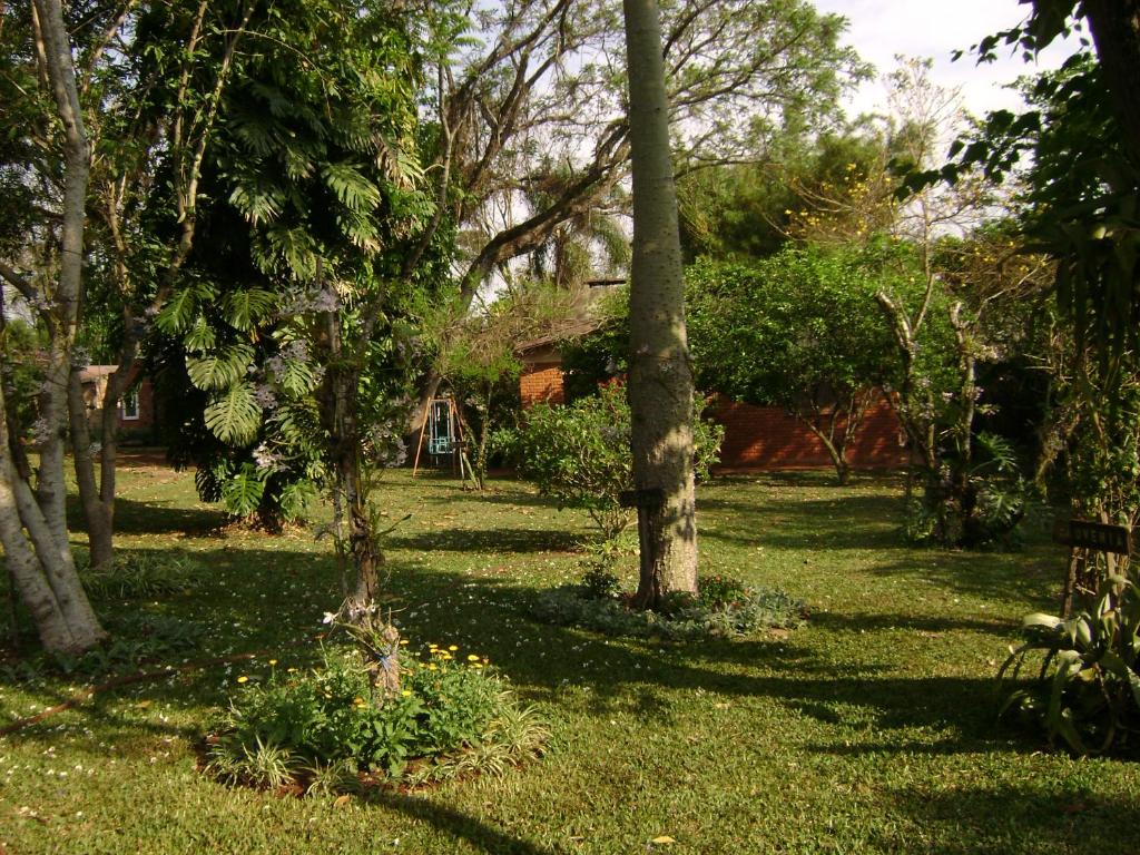 une cour avec des arbres et de l'herbe et une maison en arrière-plan dans l'établissement Hosteria Helvecia, à Montecarlo