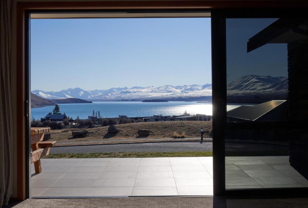 - une vue sur le lac depuis une porte en verre dans l'établissement Lake Lodge - Lake Tekapo, à Lac Tekapo