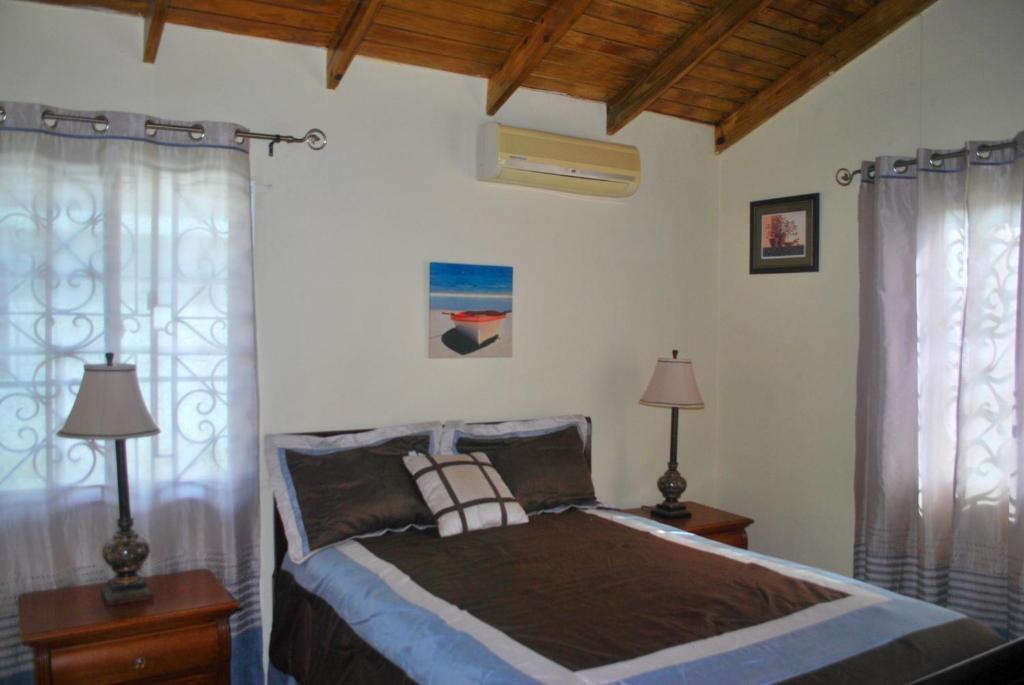 a bedroom with a bed with two lamps and two windows at Alian's Comfort Stay in Montego Bay