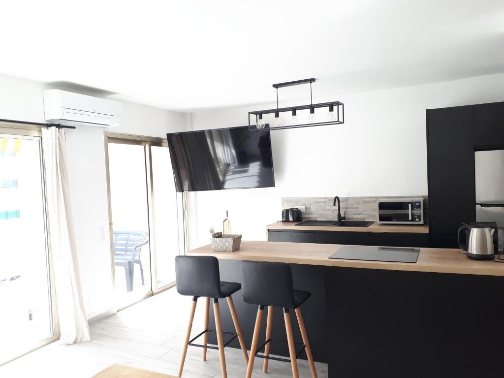 a kitchen with a counter and two stools in it at Luxe 6 couchages proxi bord de mer centre ville in Cannes