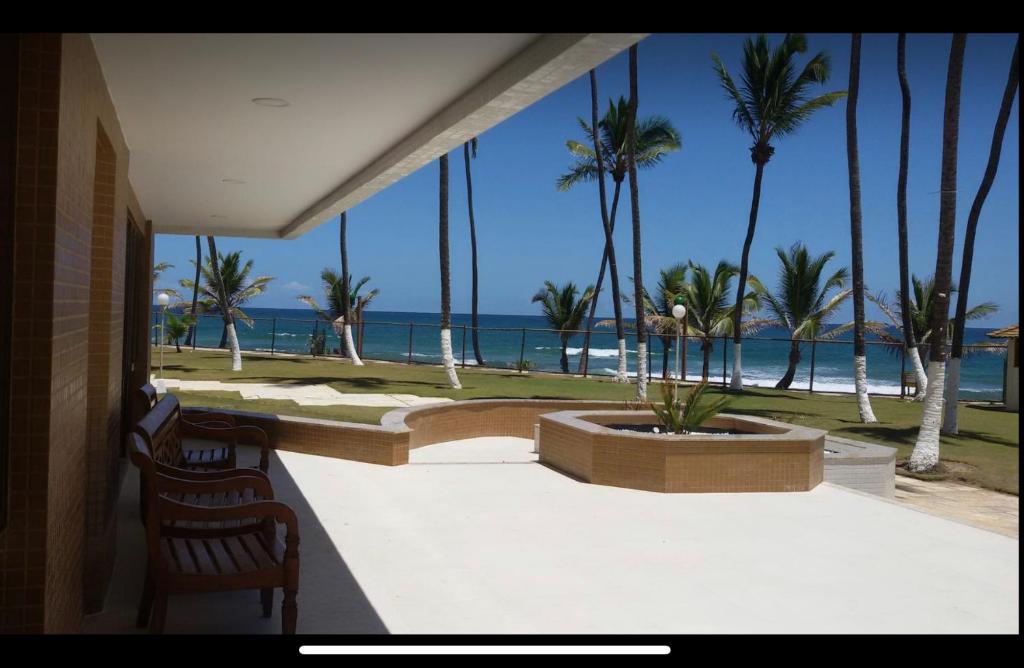 einen Balkon mit Blick auf das Meer und die Palmen in der Unterkunft Lindo Apartamento pé na areia com serviço de limpeza in Lauro de Freitas