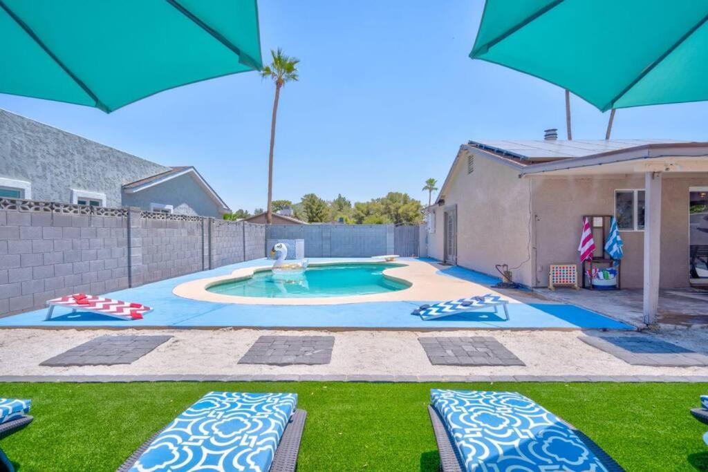 una piscina con sillas y sombrillas en un patio en Fab PHX Getaway w/ Pool & Fire Pit, en Phoenix