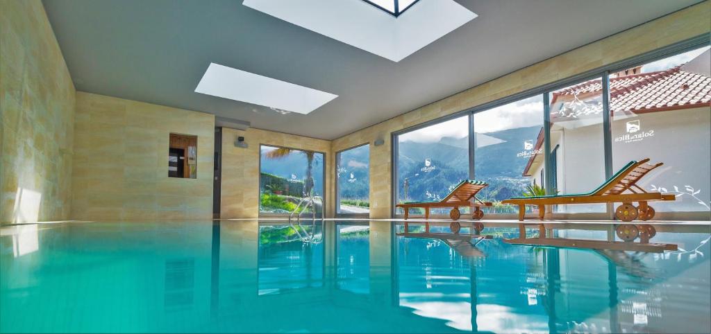 a swimming pool with two chairs and a table at Solar da Bica in São Vicente