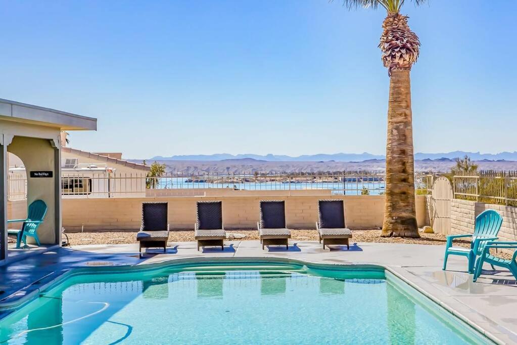 a swimming pool with chairs and a palm tree at Palm Paradise Water Views Heated Pool & Spa! in Lake Havasu City