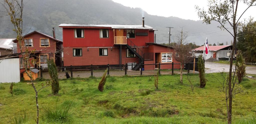 una casa roja en medio de un campo en Cabañas Robinson, en Puerto Puyuhuapi