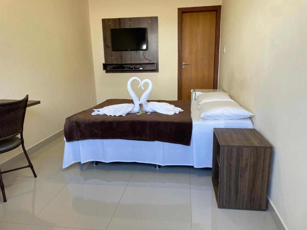 a bedroom with a bed with two white towels at Pousada Encantos de Capitolio in Capitólio