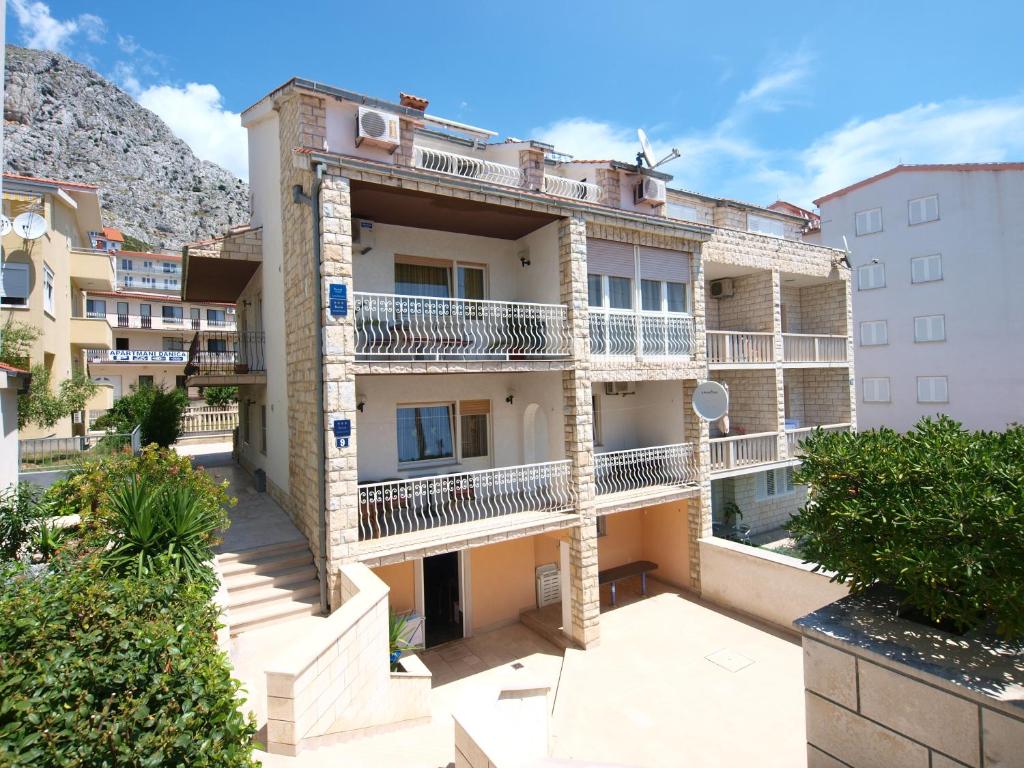 an apartment building with balconies and a mountain in the background at Apartment Sladojevic in Omiš