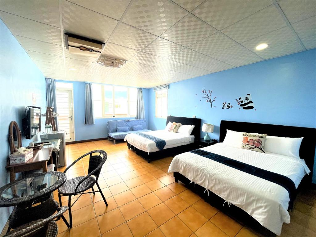 een slaapkamer met 2 bedden en een tafel en een bank bij 台東新港民宿 in Chenggong