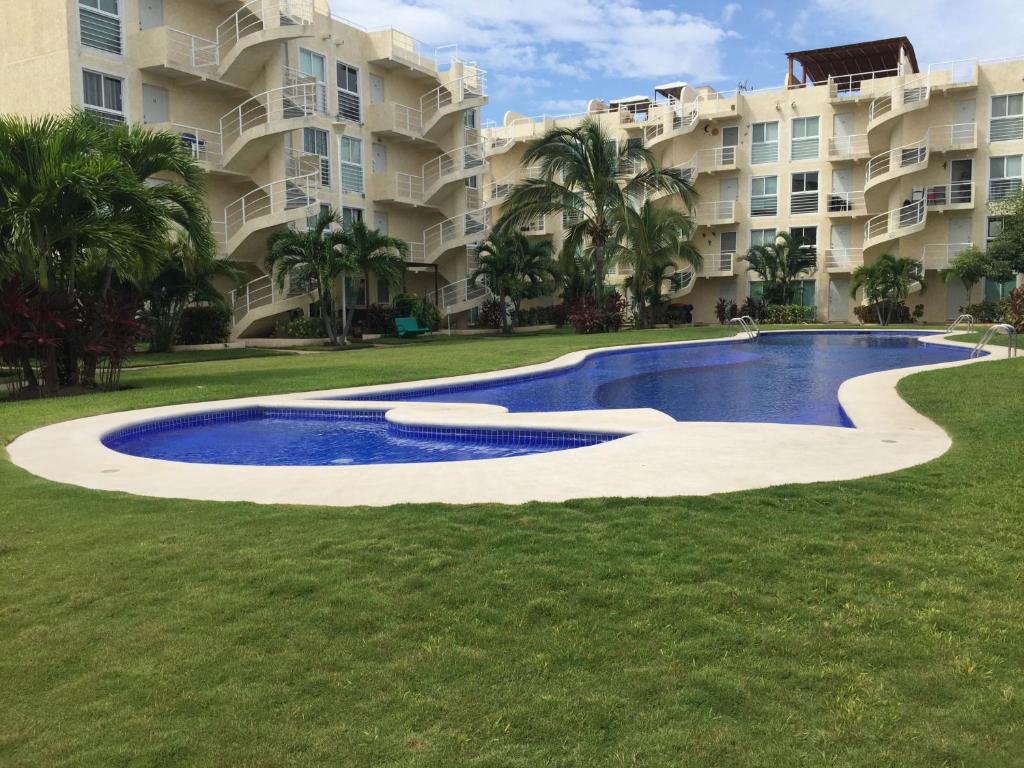 une piscine en face d'un grand immeuble dans l'établissement Acapulco, Departamento PB en Marina Diamante, à Acapulco