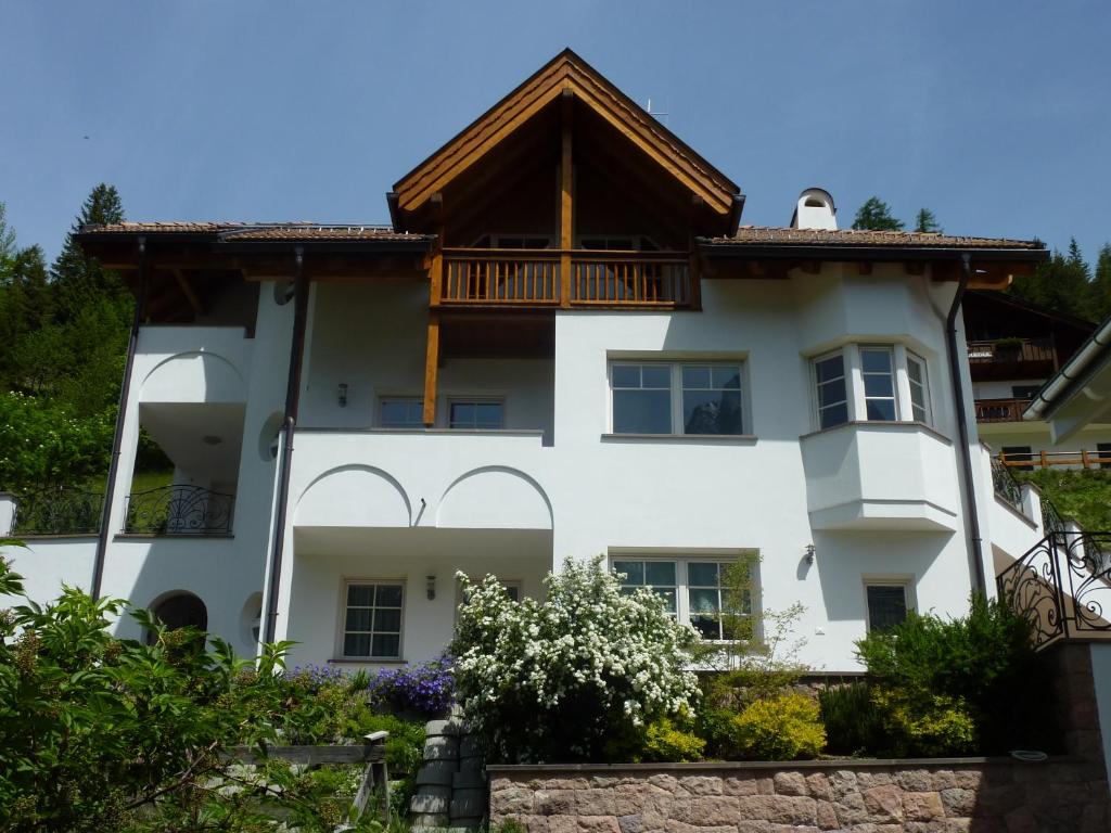 a white house with a wooden roof at Appartamenti Valpinoi in Santa Cristina Gherdëina