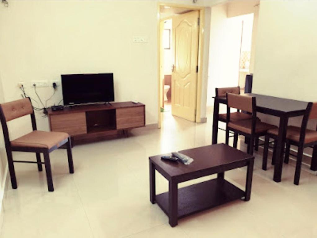 ein Wohnzimmer mit einem TV, einem Tisch und Stühlen in der Unterkunft Chippy Apartments 3006B in Chennai