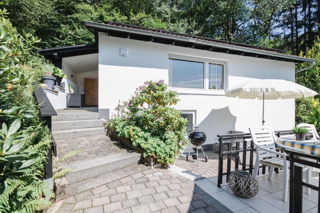 een wit huis met een patio met een tafel en een parasol bij Haus Panoramablick in Niedersalwey