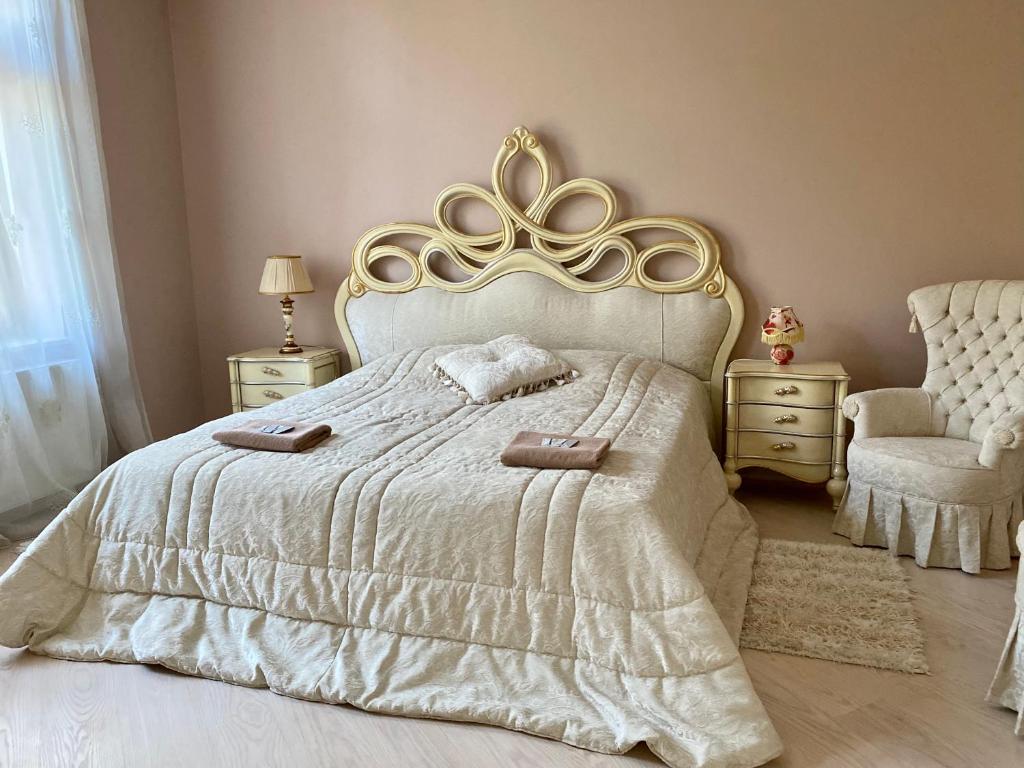 1 dormitorio con 1 cama blanca con cabecero dorado y silla en Royal Apartment, en Leópolis
