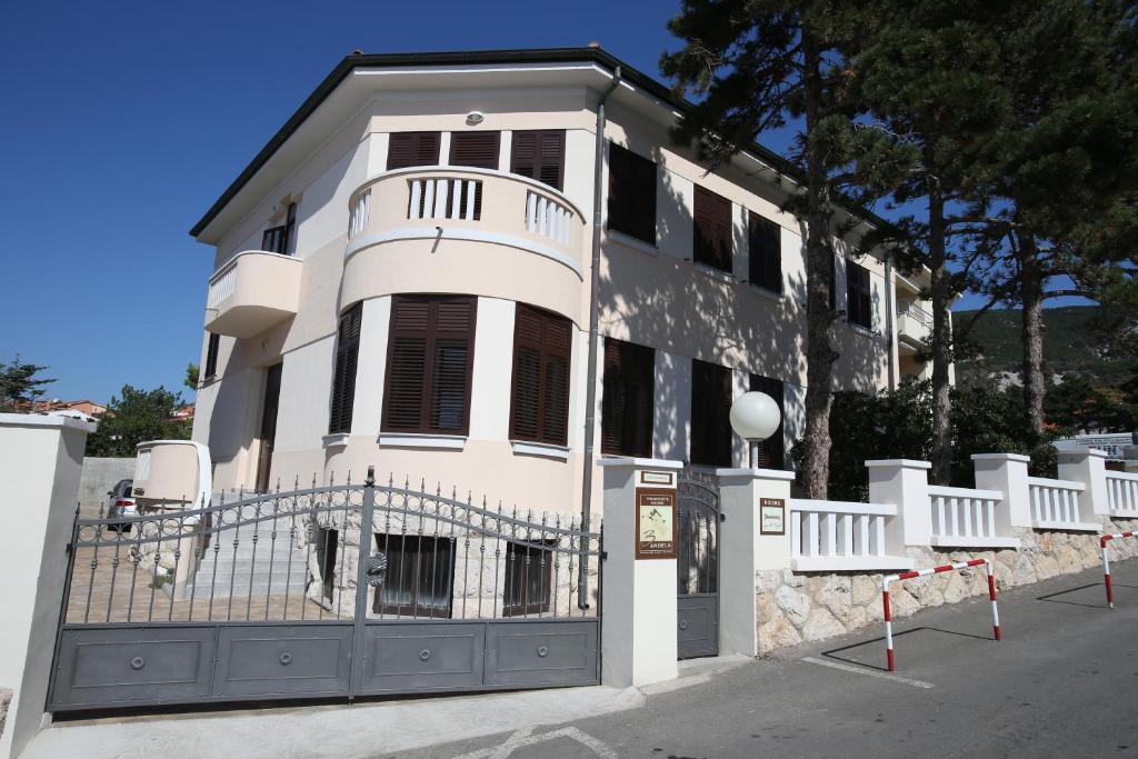a white building with a fence in front of it at Apartment & Rooms Three Angels in Baška