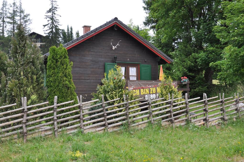 ein kleines Haus mit einem Zaun davor in der Unterkunft Weigl Hütte Semmering in Semmering