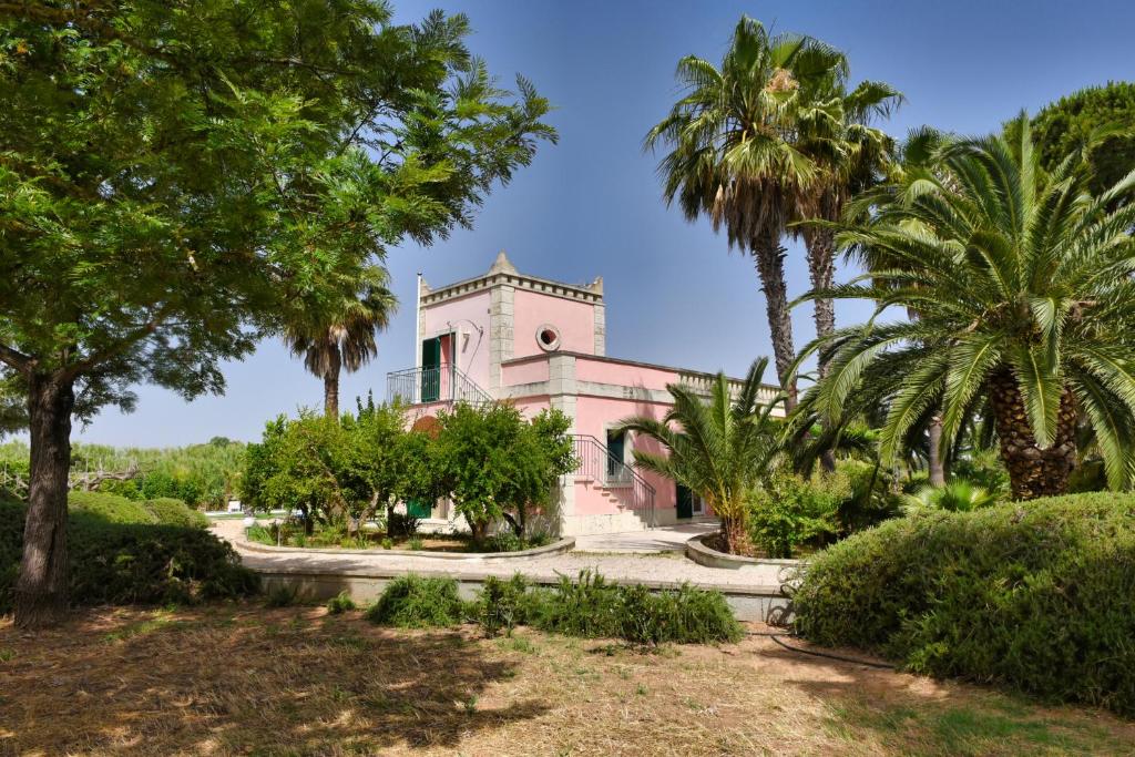 ein rosafarbenes Gebäude mit Palmen davor in der Unterkunft Villa Sirgole Rosa with Pool, Galatina in Cutrofiano