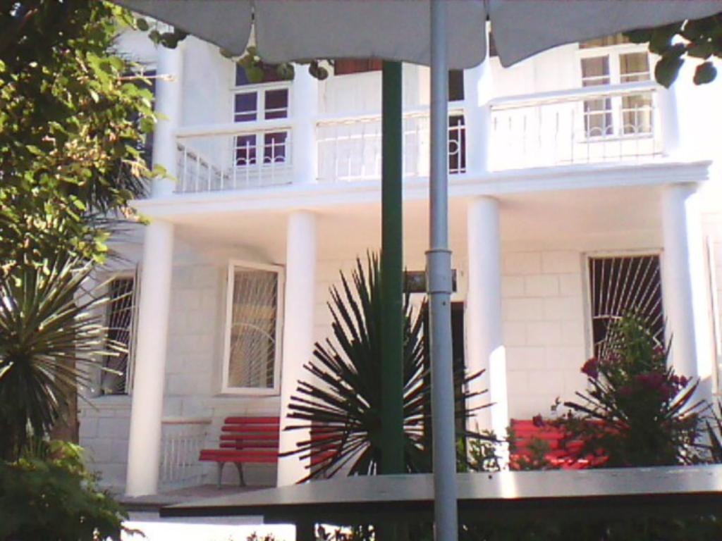 una casa blanca con un banco rojo delante de ella en White Guest House, en Batumi