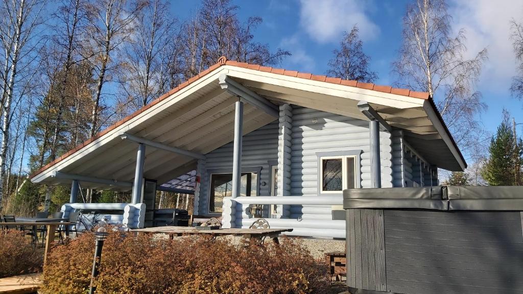 a small white cabin with a pitched roof at Järvenrantamökki Himoksella poreammeella in Jämsä