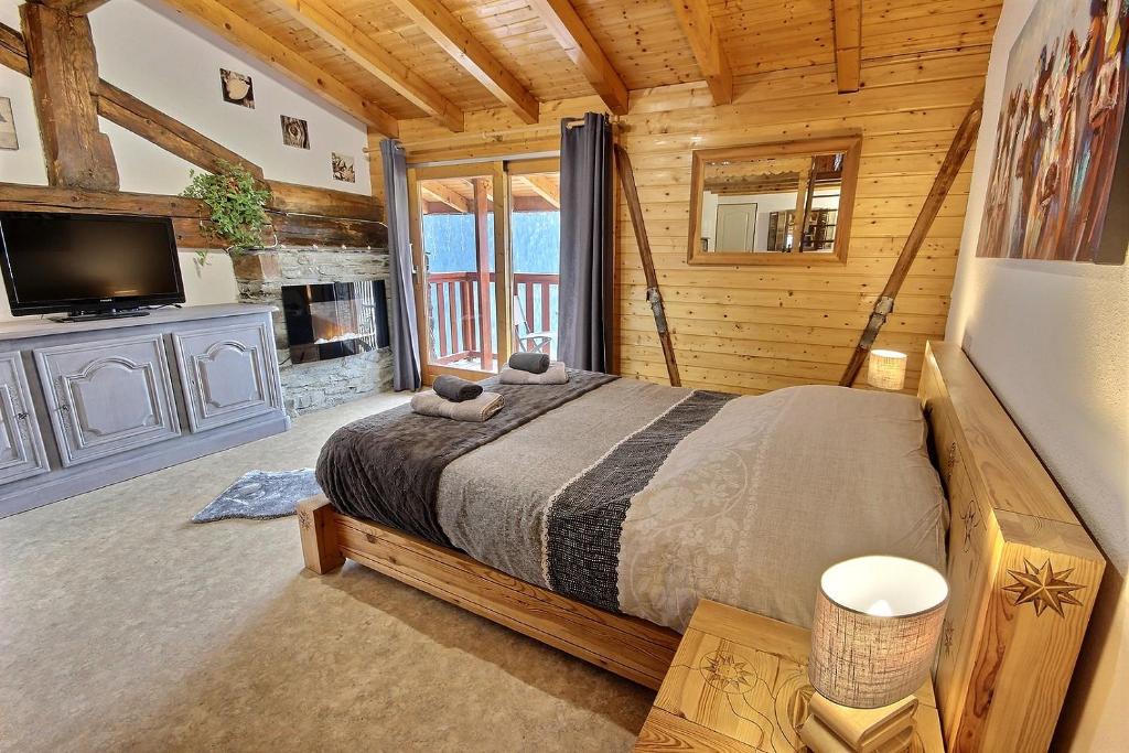 ein Schlafzimmer in einem Blockhaus mit einem Bett und einem TV in der Unterkunft Les Balcons du Molliebon in Séez