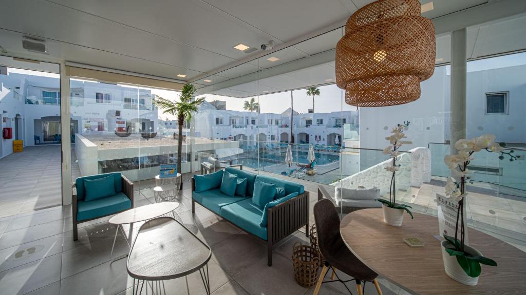 een kamer met blauwe stoelen, een tafel en een aantal ramen bij Guinate Club Apartamentos in Puerto del Carmen