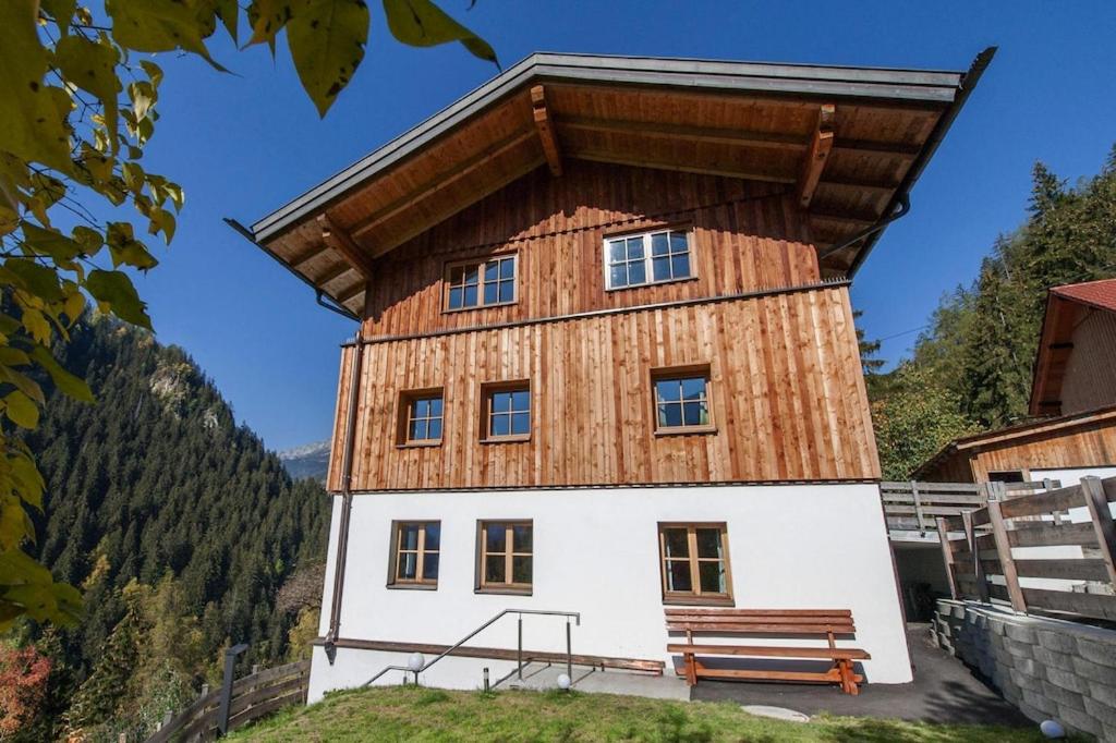 ein Gebäude mit einem Holzdach und einer Bank davor in der Unterkunft Apartments, Tobadill in Tobadill