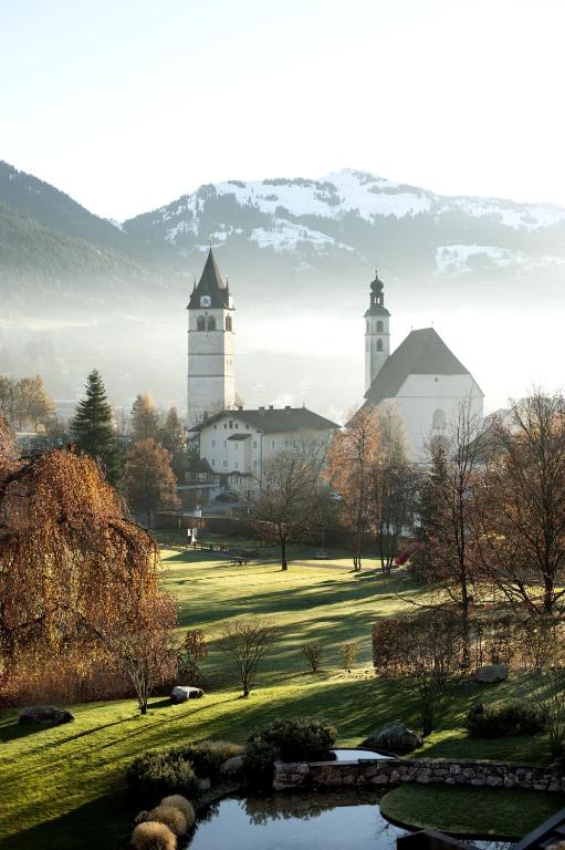 two large white buildings with a pond and two towers at Kitzhof Mountain Design Resort in Kitzbühel