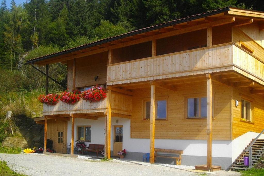 una casa in legno con fiori rossi sopra di Semi-detached house, Zell am Ziller a Zell am Ziller