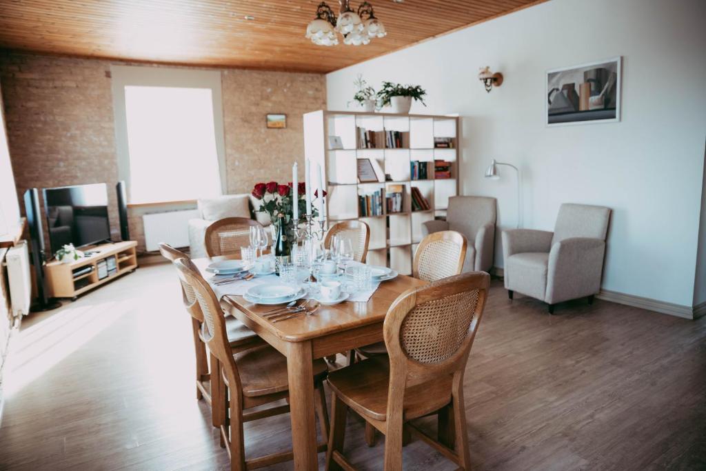 a dining room with a wooden table and chairs at RUMIDO Suite in Valmiera