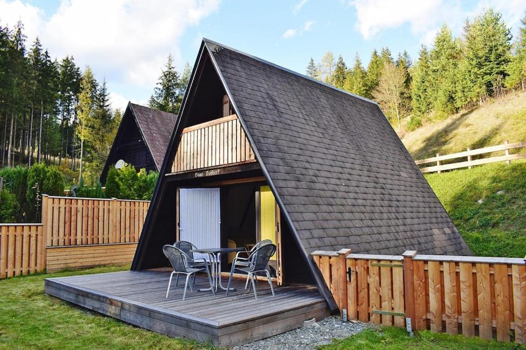 a black roofed cabin with a table and chairs on a deck at Ferienhütte Trabochersee, St Peter-Freienstein in Gmeingrube