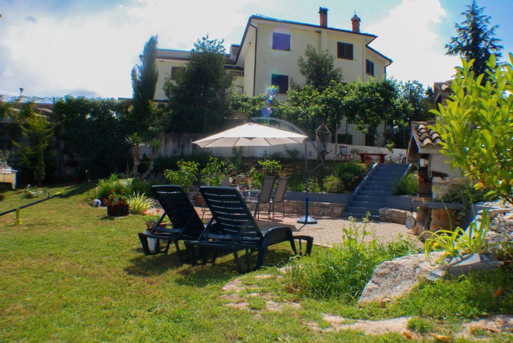dos sillas y una sombrilla en el patio de una casa en Apartments Finka Terzić, en Žbandaj